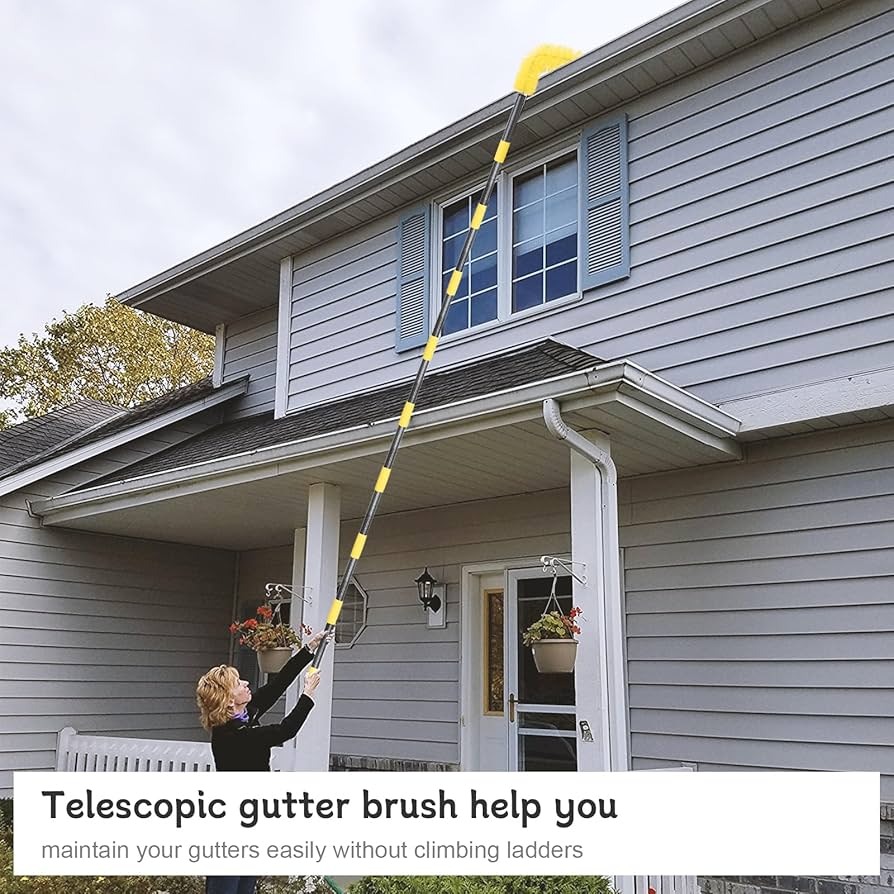 Homeowner using a long telescopic pole with a brush attachment to clean debris from second-story gutters without a ladder.